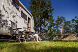 Woman resting near motorhomes in nature. Family vacation travel,