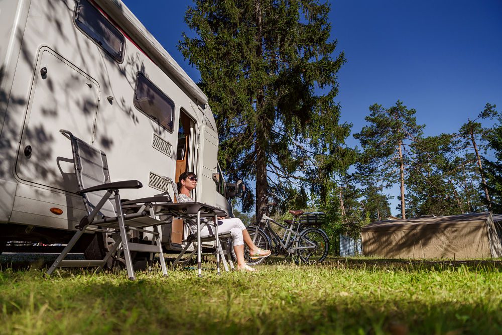 Woman resting near motorhomes in nature. Family vacation travel,